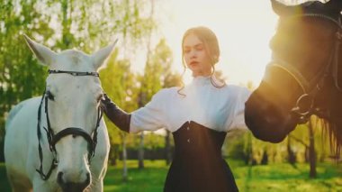 Atı olan asil, fantezi prensesi. Güzel kız güçlü surat dudaklar iki ata sarılır hayvan evcil hayvanı. Peri masalı kraliçesi kameraya bakıyor. Siyah elbiseli, eski tarz orman güneşi aydınlık sanat 4k