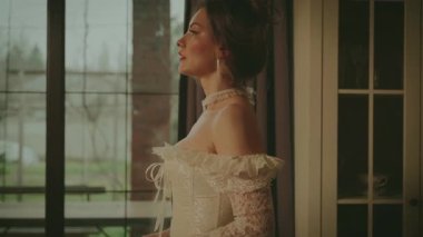 Klasik odada yürüyen genç ve seksi bir kadın aşkı beklemek için pencereye gider. Peri masalı prenses gelin yetişkin kız güzel yüzü. Peri masalı kraliyet evi beyaz klasik elbise uzun balo elbisesi eski tarz sarı saç. 4k