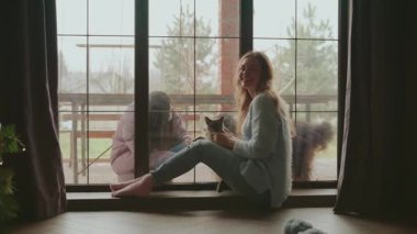 Dışardaki kişi kendini karantinaya almış hasta arkadaşını ziyaret ediyor. Güvenli iletişim, cam pencereden konuşan iki kişi. Evde kal. Mutlu kız gülen surat, komşu desteğinin keyfini çıkar.