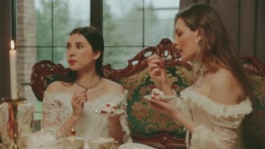 Kek yiyen bir kadın çay fincanındaki çay kaşığıyla çikolatalı kek yiyor. Kanepede oturan asil bayan kahve masası kızı oturma odasında dinleniyor. Beyaz, eski tarz, şenlikli bir akşam yemeği..