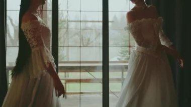 İki mutlu kadın klasik odada dans edip neşe saçan gülen yüzler takınıyorlar. Peri masalı gelin yetişkin kızlar güzel asil kadın. Kraliyet evi beyaz eski moda elbise uzun balo elbisesi eski tarz parti