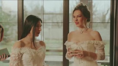 Pencereden bakan üç kadın. Soylu bayan prenses kraliyet kraliçesi klasik oda içinde. Gece uzun balo elbisesi beyaz, eski tarz elbise partisi. Sevgili baş nedimeler kitap okuyorlar..