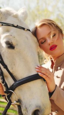 Güzel, güzel, gülümseyen yüz, kırmızı dudaklar, beyaz elli mutlu kadın, ağızlık kürküne dokunuyor, at evcil hayvanını önemsiyor. Mutlu seksi kız eski moda kıyafetler sihirli güneş ışığı dikey video.