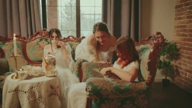 Bir grup soylu kadın çay içerken sohbet ediyorlar, eski tarz koltukta oturuyorlar. Üç arkadaş kitap romanını tartışıyorlar. Mutlu Kız oturma odası. Üç sosyete kızı baş nedime..