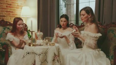 Kek yiyen bir kadın çay fincanındaki çay kaşığıyla çikolatalı kek yiyor. Kanepede oturan asil bayan kahve masası kızı oturma odasında dinleniyor. Beyaz, eski tarz, şenlikli bir akşam yemeği..