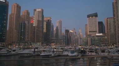 Panoramik manzara, turistik tatil beldesi, Arap şehri Dubai Marina. Modern yüksek binalar gökdelenler. Su rıhtımında beyaz deniz yatları. Güzel, parlak gün batımı, koyu mavi gökyüzü. BAE 2020