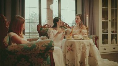 Grup soylu kadınları çay içerek sohbet ediyorlar eski tarz koltukta oturuyorlar. Üç arkadaş kitap okuyor ve dedikodu yapıyorlar. Mutlu Kız oturma odası Victoria tarzı ortaçağ elbisesi. Aristokrat sosyete kızları