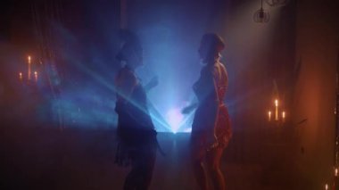 Mavi turuncu ışık, koyu siyah siluet. Gece kulübünde dans eden iki mutlu kadın. Seksi neşeli kızlar dans pistinde eğleniyor. 1920 'lerin yeni yılı. Kükreyen yirmili yıllar tarzı.