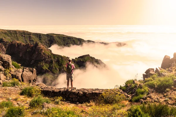 Jovem macho com uma mochila em pé em uma montanha — Fotografia de Stock