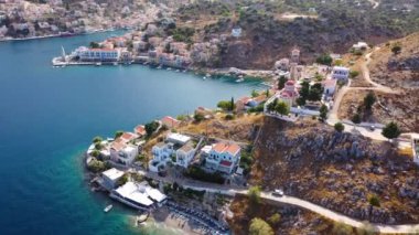 Symi (Simi) ada limanı, klasik gemi yatları, ada tepelerindeki evler, Ege Körfezi manzarası. Yunanistan adaları Rodos adasından tatil turları düzenliyor. Symi, Yunanistan, Dodecanese.