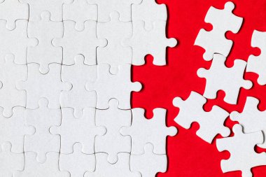 Beyaz yapboz. Renkli arka planda beyaz yapboz parçaları. Renk arkaplanındaki tamamlanmamış beyaz yapboz parçaları. 