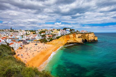 Portekiz, Algarve 'de güzel plajlı Carvoeiro balıkçı köyü manzarası. Portekiz kıyısında renkli evleri olan Carvoeiro kasabasındaki plaj manzarası. Algarve Portekiz 'deki Carvoeiro köyü..