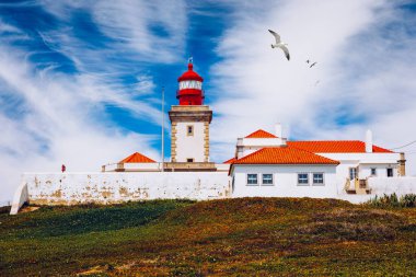 Cabo da Roca 'daki deniz feneri. Portekiz 'in güzel bir yaz gününde Sintra' da Atlantik Okyanusu kıyısındaki kayalıklar ve kayalar. Cabo da Roca, Portekiz. Atlantik Okyanusu üzerindeki deniz feneri ve kayalıklar.