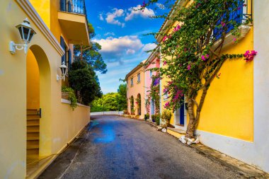 Traditional street with greek houses with flowers in Assos, Kefalonia island. Traditional colorful greek houses in Assos village. Blooming fuchsia plant flowers. Kefalonia island, Greece clipart
