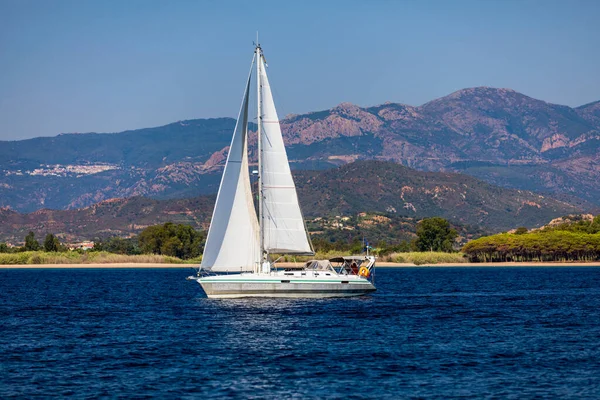 Aerial view of anchored sailing yacht in emerald sea. Aerial view of a boat. Outdoor water sports, yachting. Aerial view of anchoring yacht in open water. Ocean and sea travel and transportation