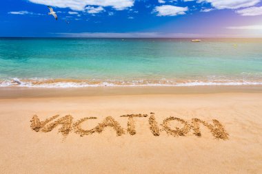 Plajda bir tatil mesajı. Kumlu bir tropik plajda yazılmış bir tatil. Sahildeki kumlara yazılmış 