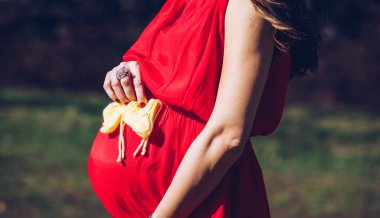 Bebek bekleyen genç bir çift. Erkek bebek ayakkabısı giyen bir aile bekliyor. Müstakbel ebeveyn kavramı. Ebeveynlerin ayakkabıları ve bebek bekleyen ayakkabıları. Annem, babam ve gelecekteki bebek ayakkabıları..