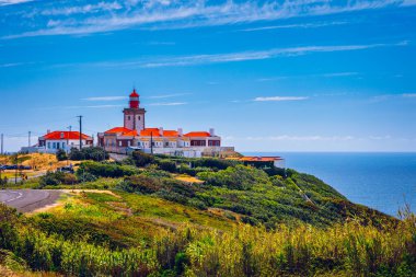 Cabo da Roca 'daki deniz feneri. Portekiz 'in güzel bir yaz gününde Sintra' da Atlantik Okyanusu kıyısındaki kayalıklar ve kayalar. Cabo da Roca, Portekiz. Atlantik Okyanusu üzerindeki deniz feneri ve kayalıklar.
