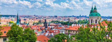 Prag 'ın kırmızı çatıları ve Prag' ın tarihi eski kasabasının düzinelerce kulesi. Güneşli bir günde Prag şehri manzarası. Arka planda kırmızı çatılar, kuleler ve Charles Köprüsü ve Vltava Nehri. Prag, Çek Cumhuriyeti.