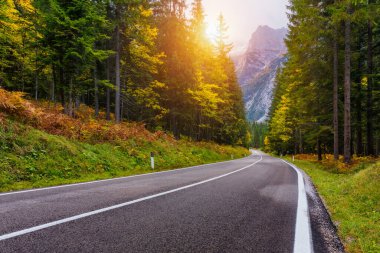 Dağ yolu. Kayalıklı manzara, bulutlu güneşli gökyüzü ve yazın akşamları güzel asfalt yollar. Klasik tonlama. Seyahat geçmişi. Dağlarda otoyol.  