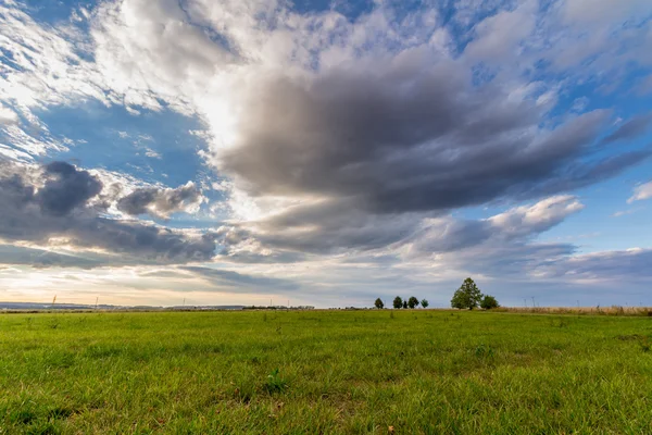 Pôr-do-sol dramático sobre campo verde — Fotografia de Stock