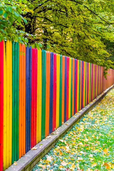 Multi colored rainbow wooden fence in autumn — Stock Photo, Image