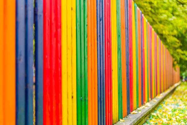 Multi colored rainbow wooden fence in autumn — Stock Photo, Image