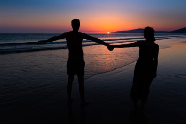 Gün batımında romantik çift bir plaj zevk yürümek