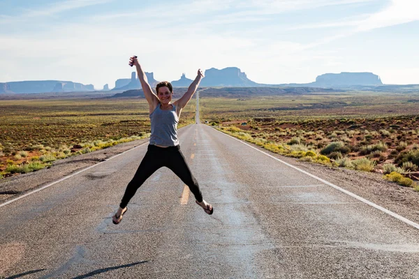 Flickan hoppar på väg nära Monument Valley i Utah — Stockfoto