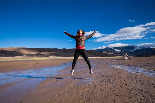Дівчина, стрибки поблизу великий пісок дюн національного парку — стокове фото