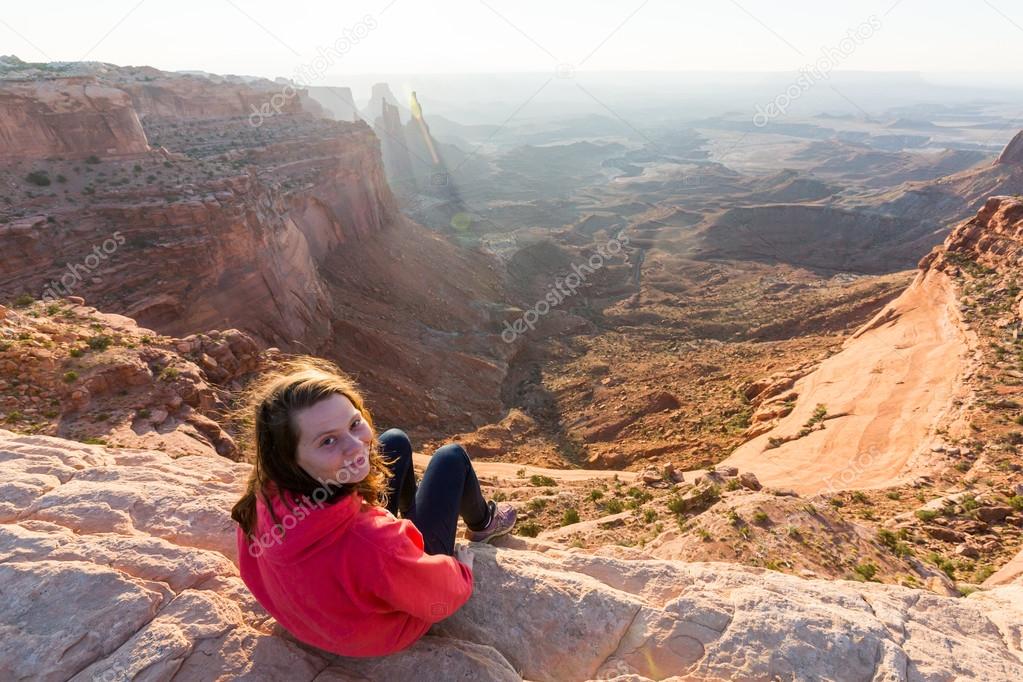 Girl sitting at the Mesa Arch at sunrise