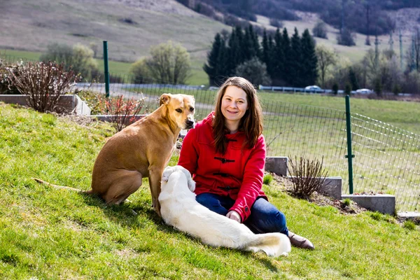 Молода жінка з собаками в саду — стокове фото
