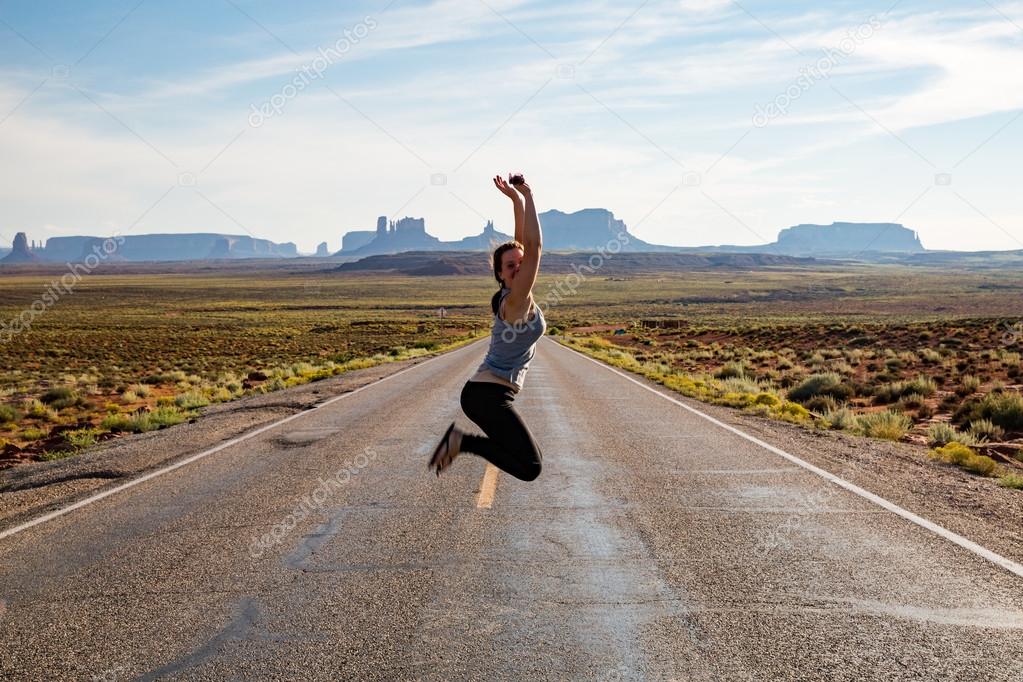 Jumping girl on the road near Monument Valley