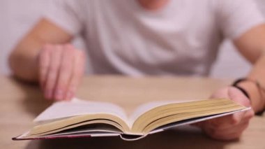 Kitap aracılığıyla leafing beyaz t-shirt giyen