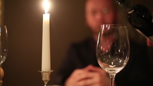 Склянка і свічка крупним планом і людина на фоні — стокове відео
