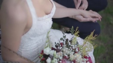 Çiçeklerle oturan ve damadın elini tuttuğunu bride