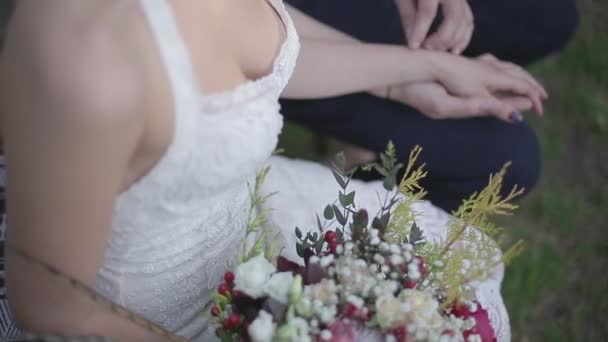 De bruid zit met bloemen en bezit is van de hand van de bruidegom — Stockvideo