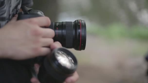 Homem segura uma câmera e lente close-up — Vídeo de Stock