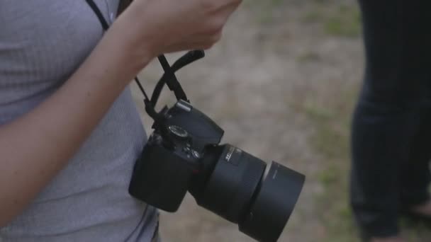 Girl with the camera on her neck looking at smartphone — Stock Video