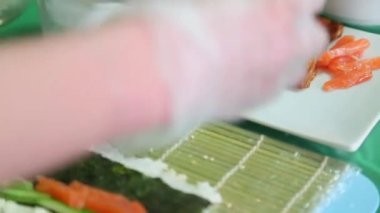 Sushi ustası bir kırmızı balık nori koyar.