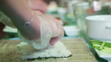 Sushi ustası pirinç üzerinde nori koyar.