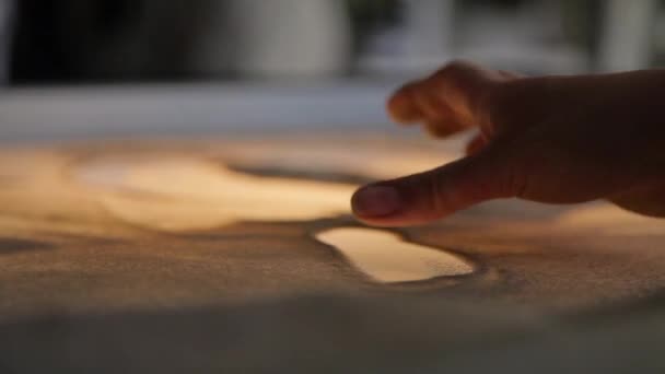 Meisje trekt schilderij met zand op het glas — Stockvideo