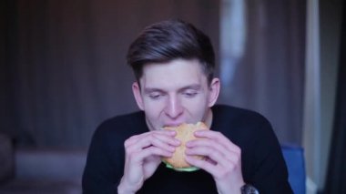 Esmer adam yeme hamburger ve gülüyor