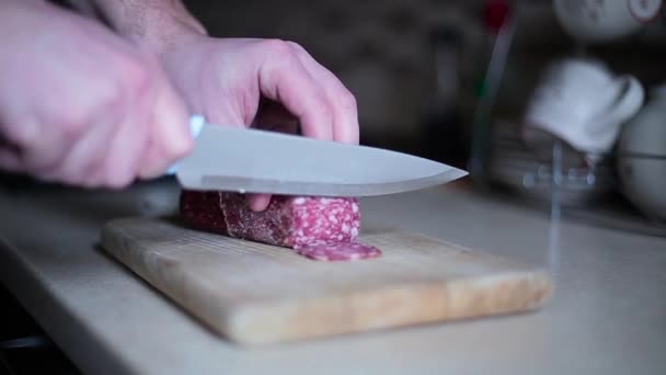 Парень нарезал колбасу на доске крупным планом — стоковое видео