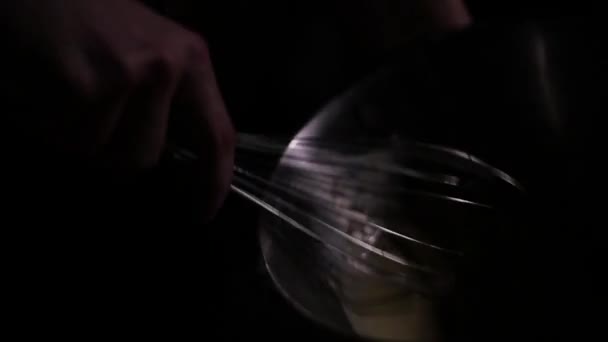 Человек в темноте кладет яйца в тарелку — стоковое видео