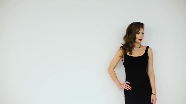 Mooi meisje in een zwarte jurk poseren op een witte achtergrond — Stockvideo