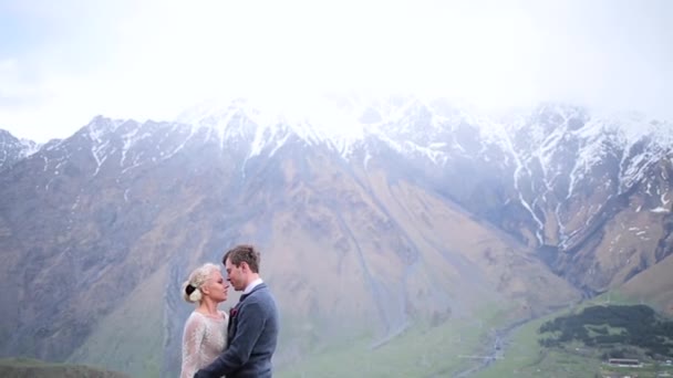 Пара поцелуев на фоне гор — стоковое видео