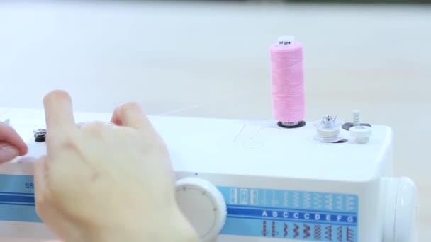 Pembe bir iplik dikiş makinesi üzerinde giyen kadın — Stok video
