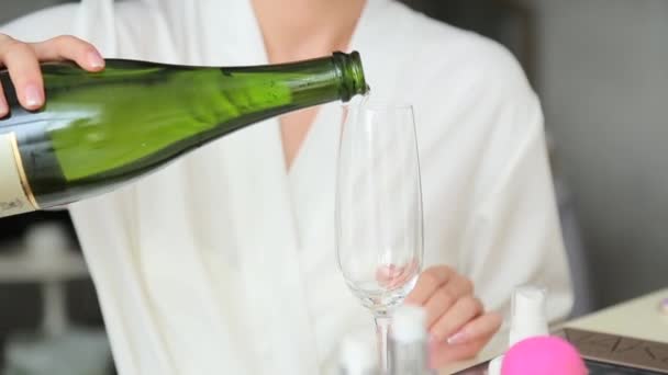 Woman in bathrob pours shampagne into glass — Stock Video