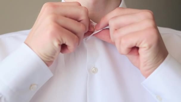 Мужчина застегивает белую рубашку крупным планом — стоковое видео